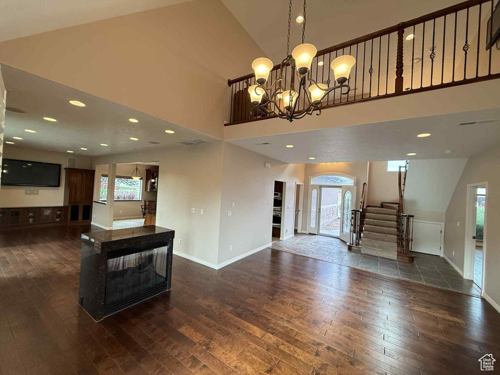 Unfurnished living room featuring dark wood finished floors, healthy amount of natural light, and a towering ceiling