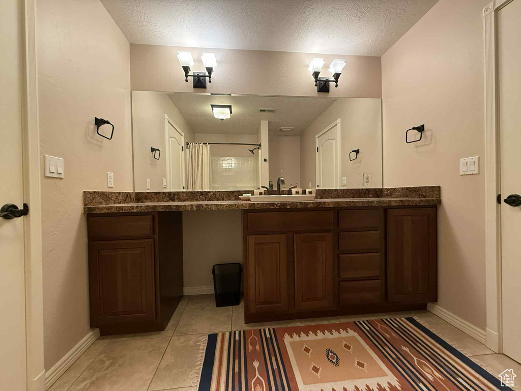 Bathroom with vanity, baseboards, a shower, and a textured ceiling