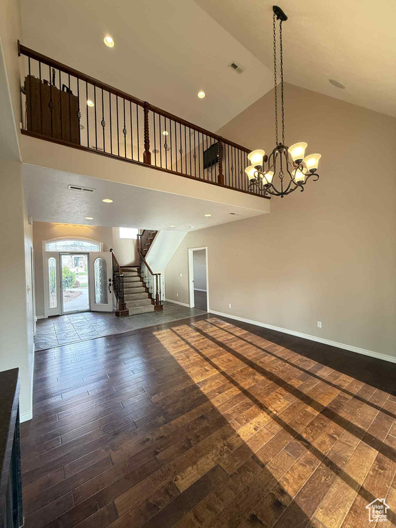 Unfurnished living room with dark wood-type flooring, stairway, high vaulted ceiling, baseboards, and recessed lighting