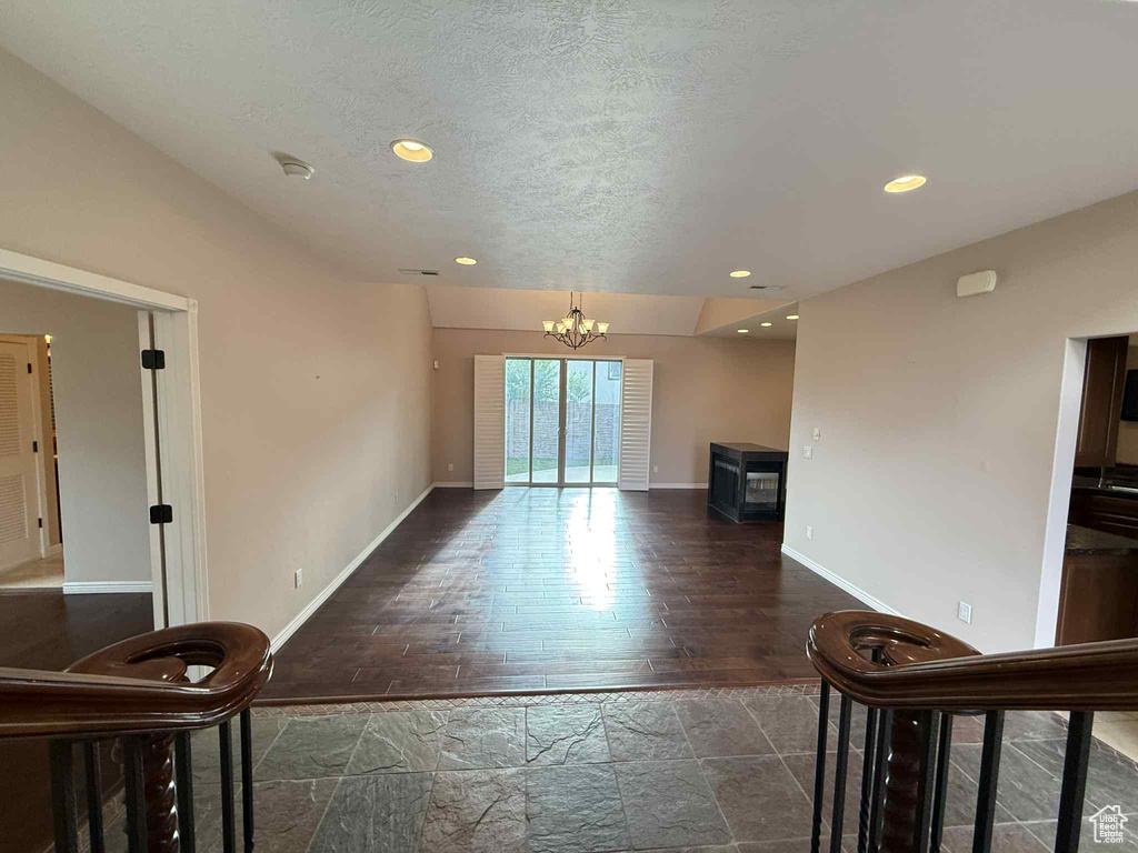 Living area with a chandelier, baseboards, stone tile floors, recessed lighting, and a textured ceiling