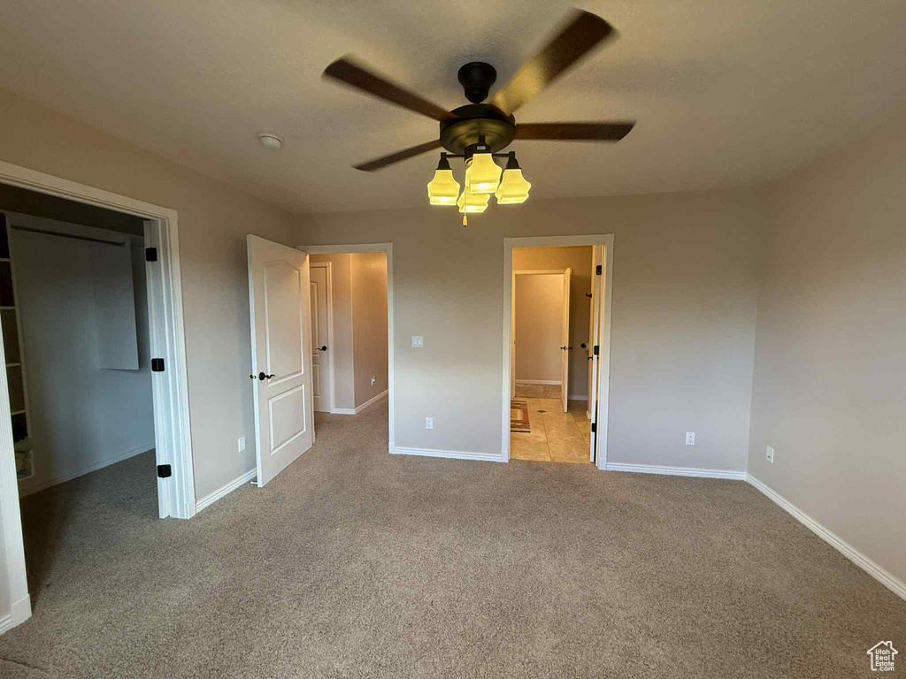Unfurnished bedroom featuring baseboards, carpet flooring, a spacious closet, and a ceiling fan