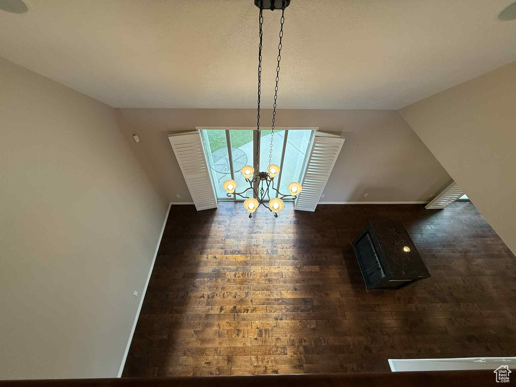 Unfurnished dining area with wood finished floors, baseboards, and a chandelier