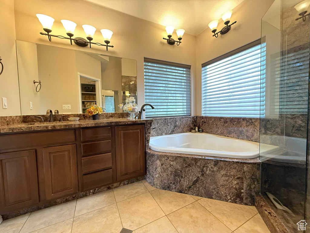 Bathroom featuring healthy amount of natural light, a bath, double vanity, and tile patterned floors