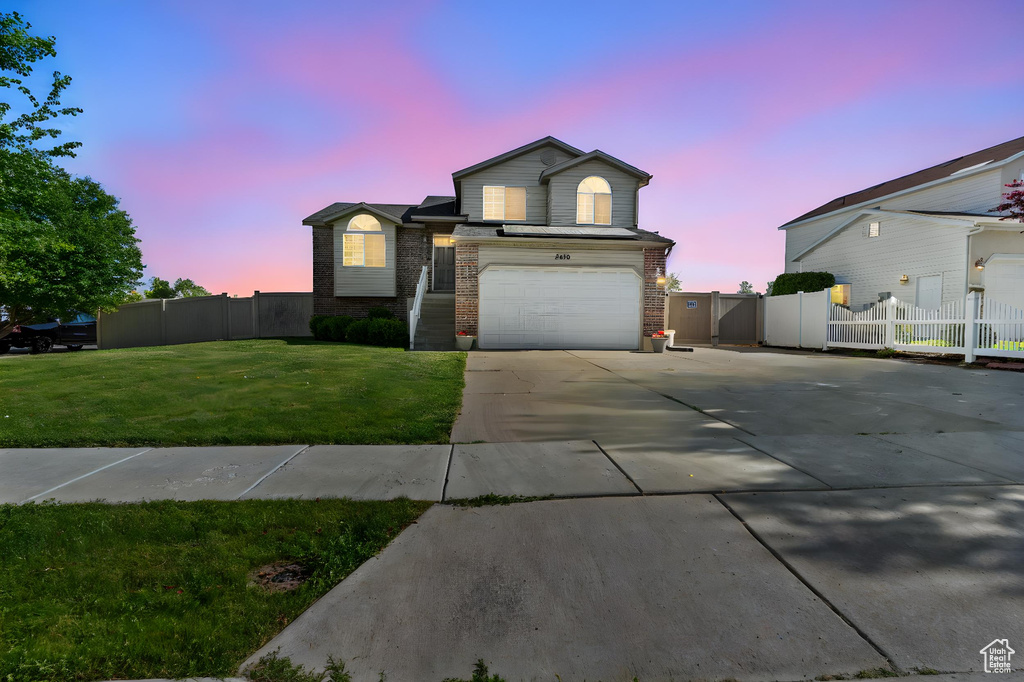 View of front of property featuring driveway, a garage, brick siding, and a gate