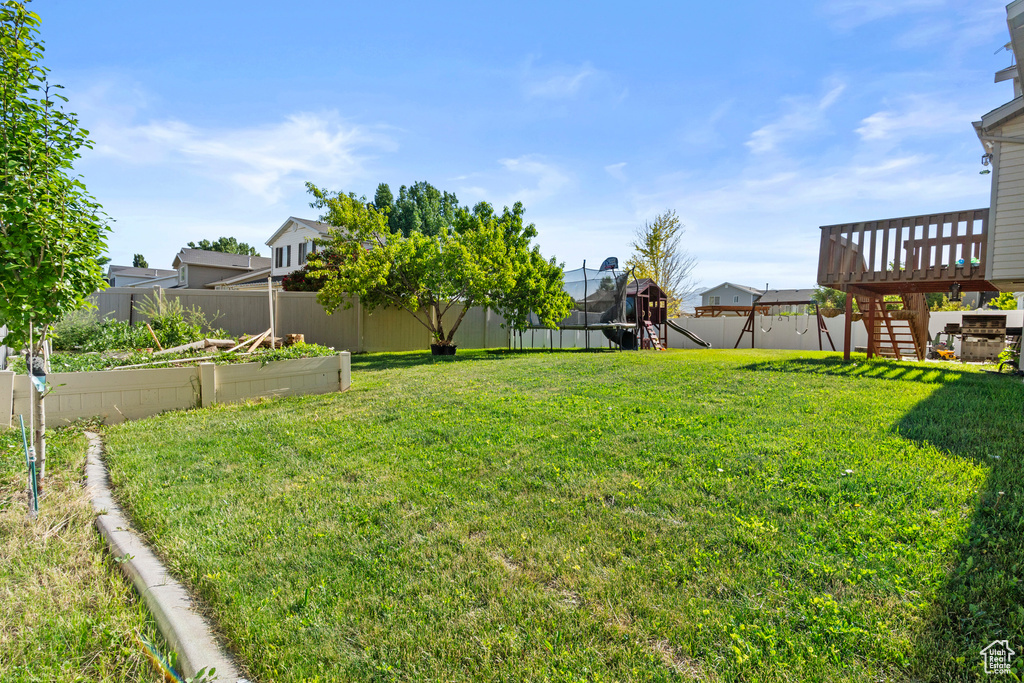 View of yard featuring a garden, a playground, stairway, and a deck