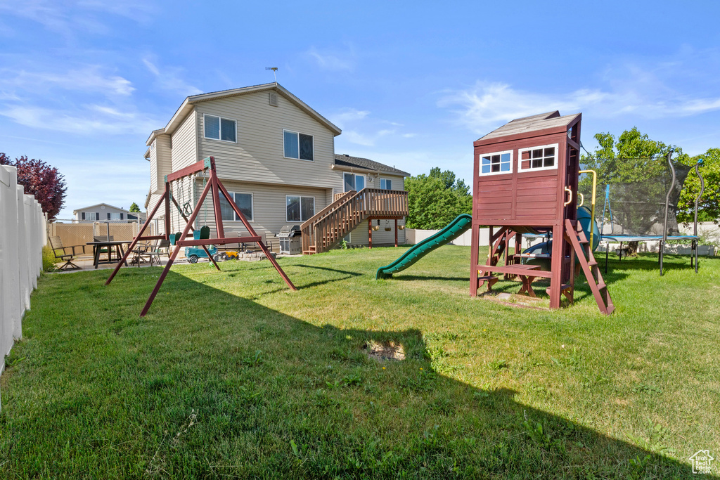 Back of property featuring a trampoline and a playground