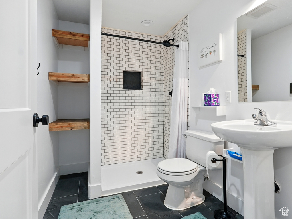 Full bath featuring toilet, a shower stall, tile patterned floors, and a sink
