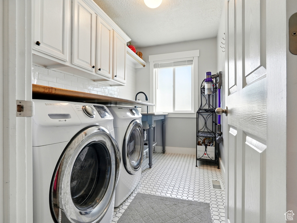 Laundry room with cabinet space, independent washer and dryer, baseboards, and a textured ceiling