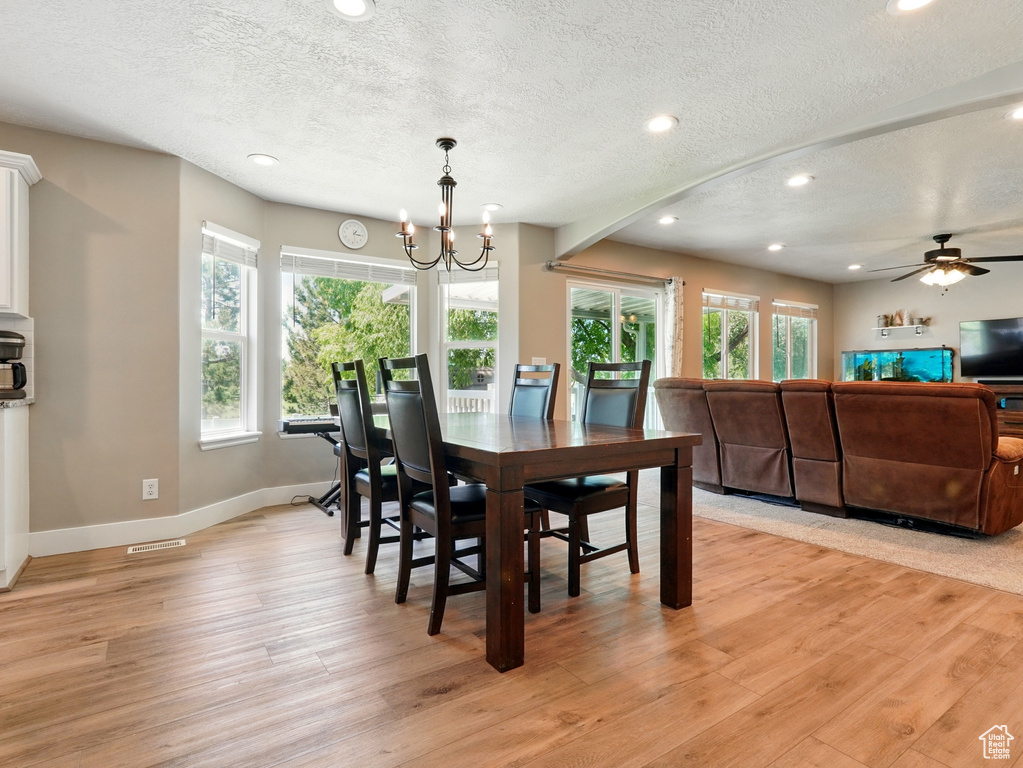 Dining area featuring baseboards, light wood-type flooring, a textured ceiling, recessed lighting, and a chandelier