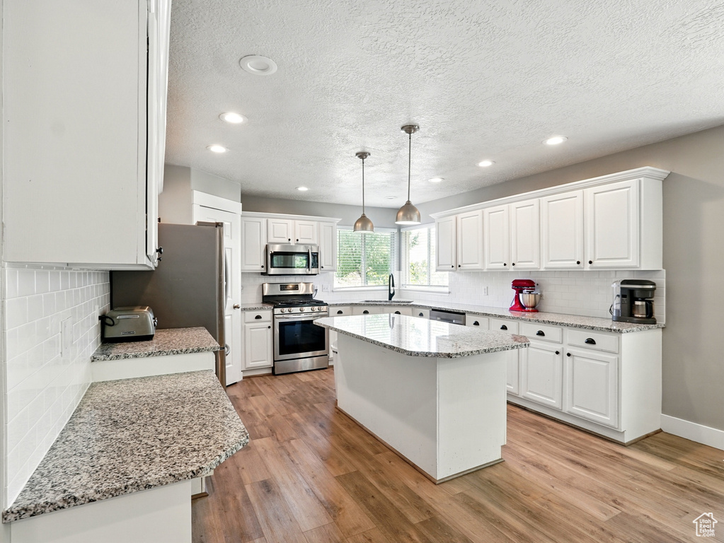 Kitchen featuring appliances with stainless steel finishes, a sink, a textured ceiling, recessed lighting, and backsplash