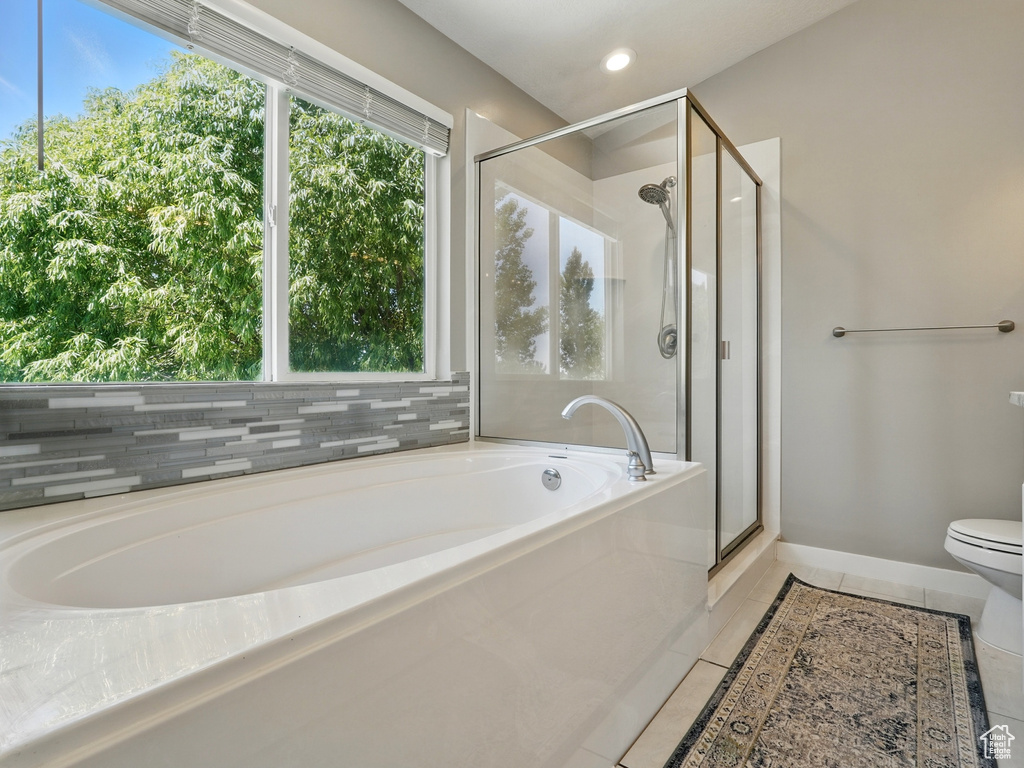 Full bath with a garden tub, a shower stall, tile patterned floors, toilet, and baseboards