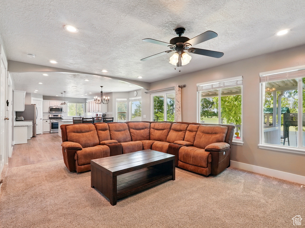 Living area featuring recessed lighting, light carpet, a chandelier, baseboards, and ceiling fan