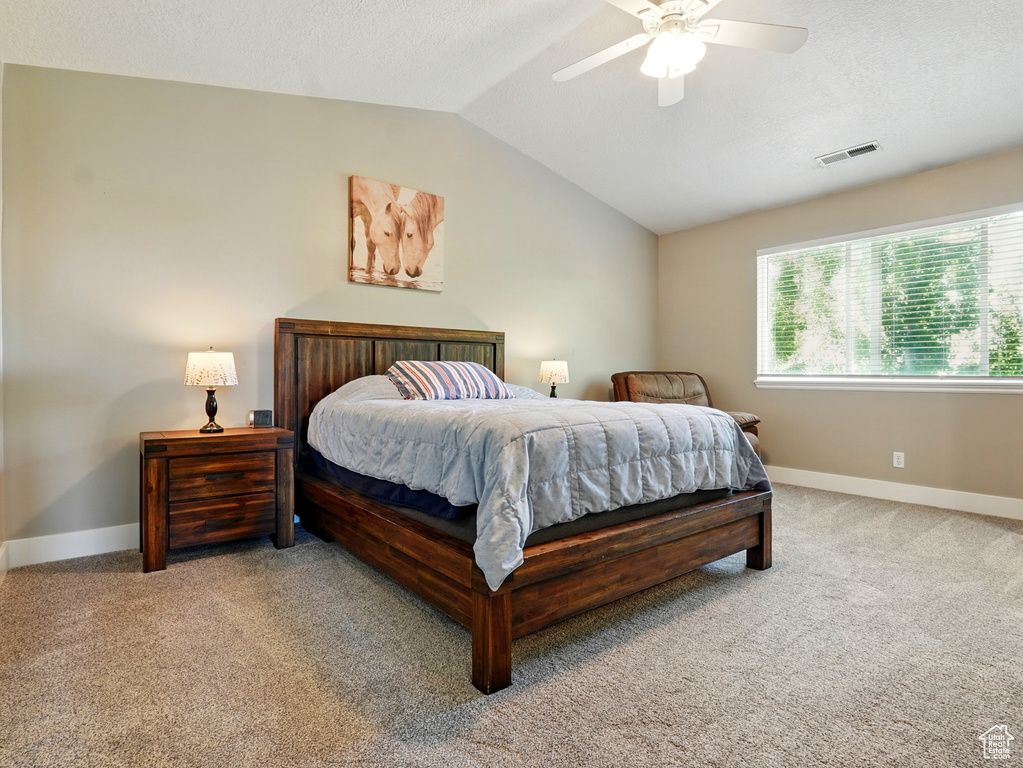 Carpeted bedroom with lofted ceiling, baseboards, and ceiling fan