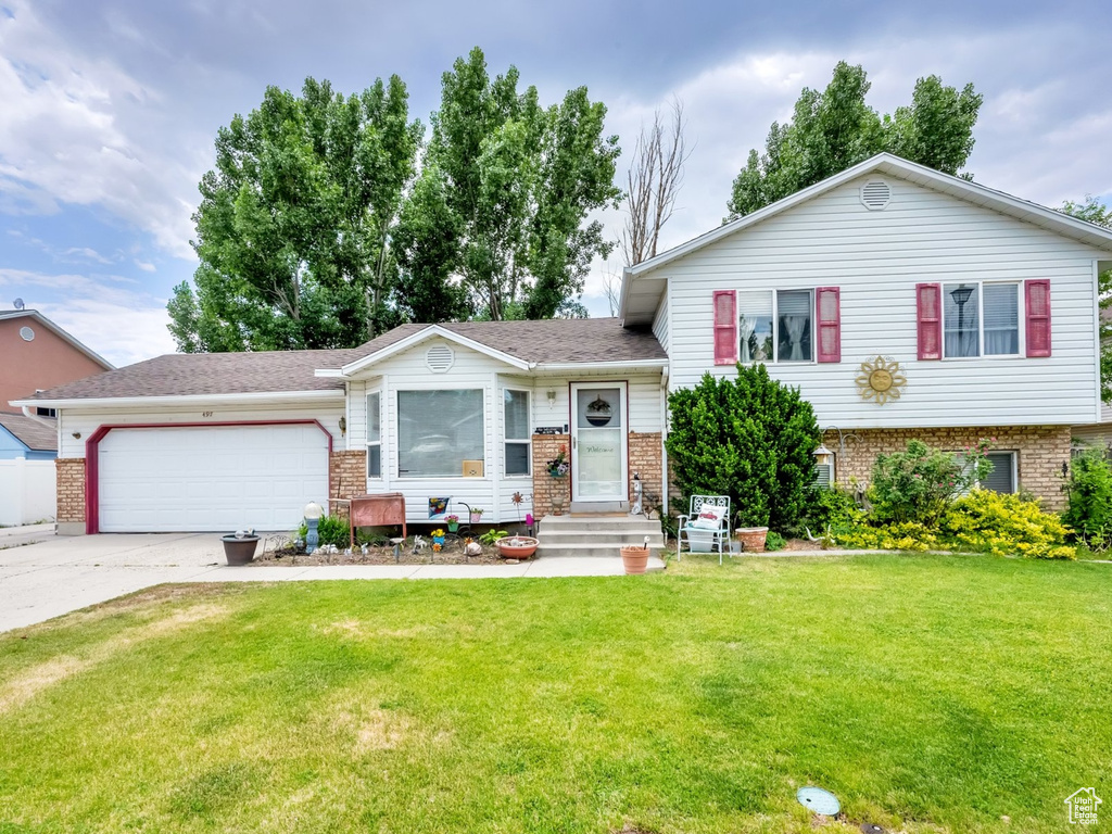 Split level home with brick siding, concrete driveway, and a garage