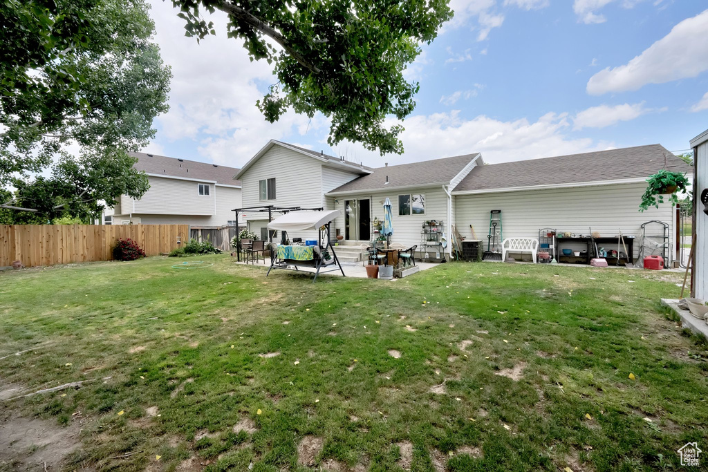 Rear view of property featuring a patio area, entry steps, and a shingled roof