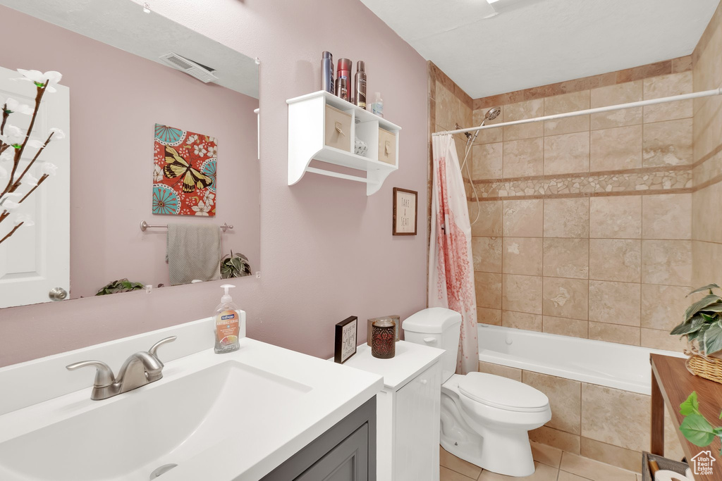 Bathroom featuring vanity, tile patterned floors, tiled shower / bath, and toilet