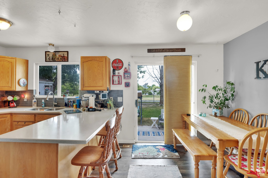 Kitchen with a sink, a breakfast bar area, tasteful backsplash, and wood finished floors