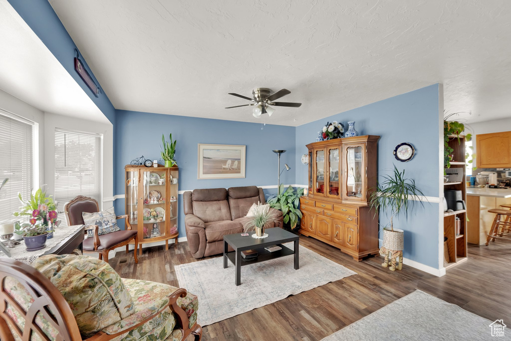 Living area featuring a ceiling fan, wood finished floors, and baseboards