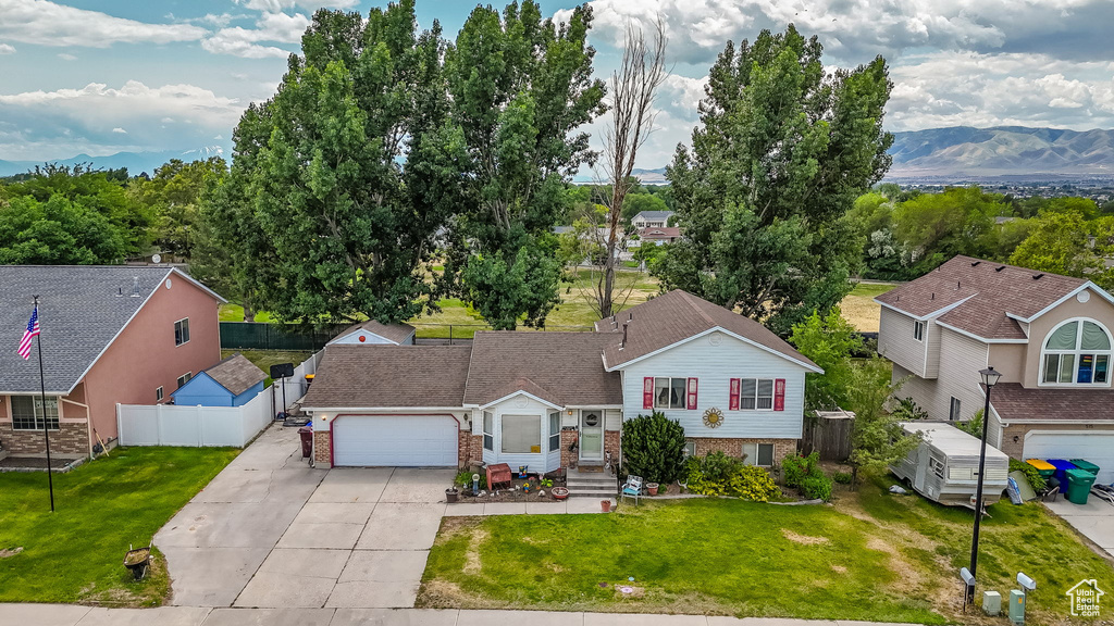 View of front of house featuring concrete driveway, brick siding, an attached garage, and a mountain view