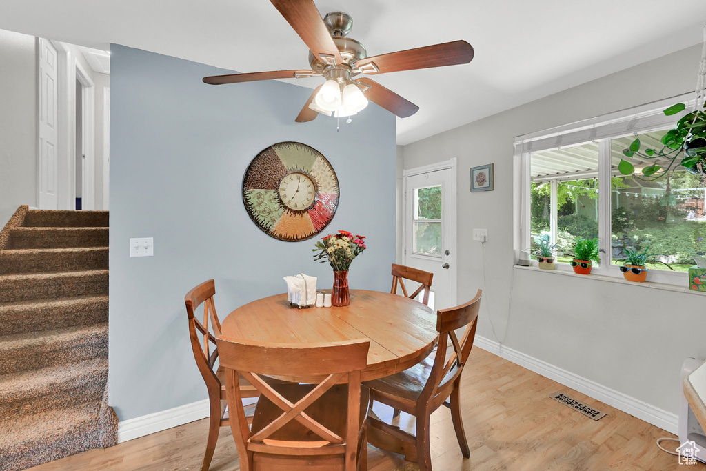 Dining space featuring ceiling fan, light wood finished floors, baseboards, and stairway