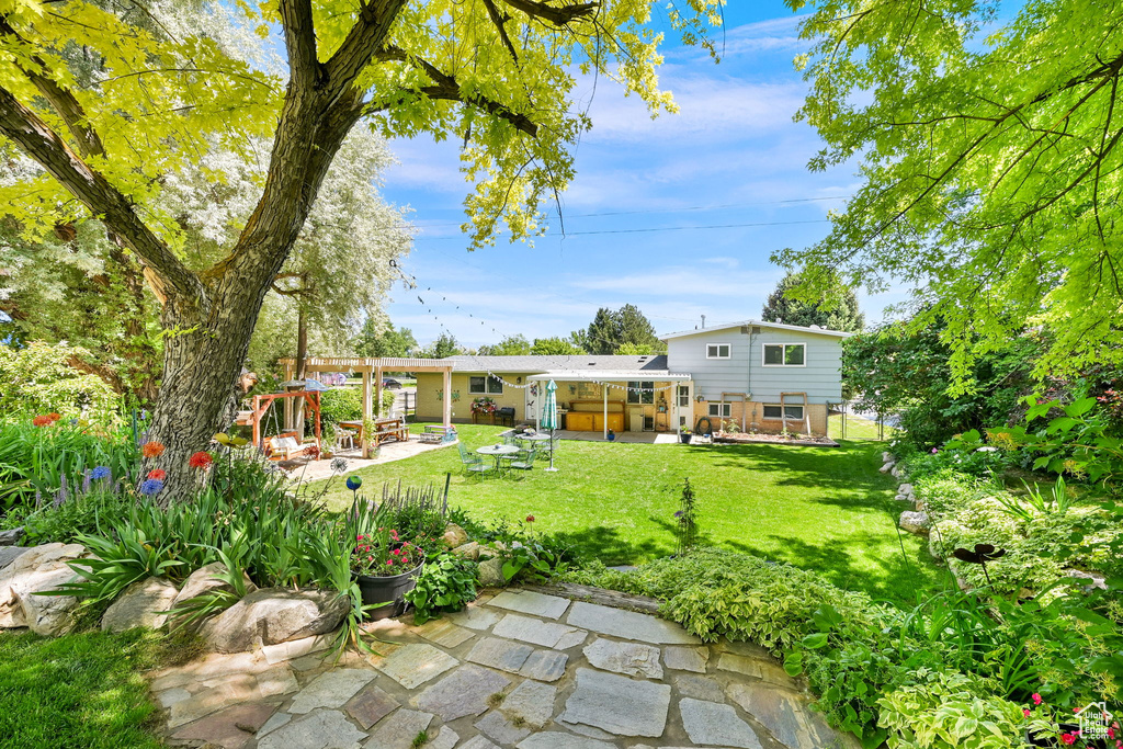 View of green lawn featuring a patio, a pergola, and a sunroom