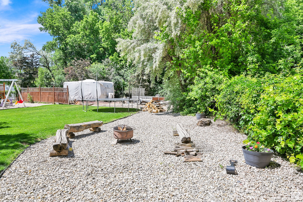 View of yard with a fire pit, a playground, and a trampoline