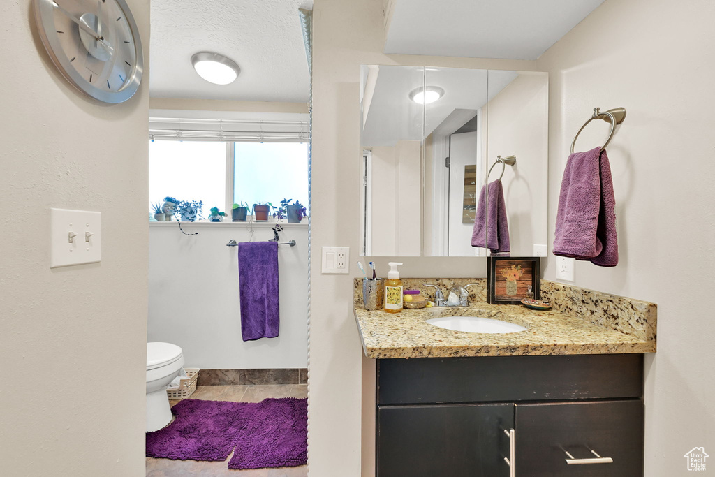 Bathroom with vanity, toilet, baseboards, and tile patterned floors