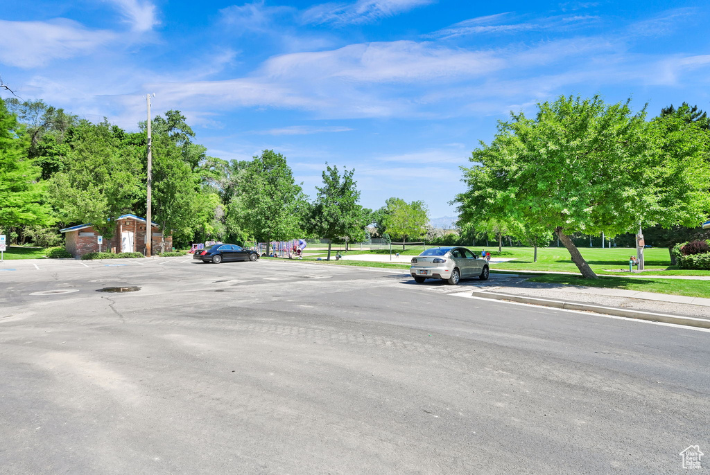 View of asphalt street featuring sidewalks, curbs, and view of scattered trees