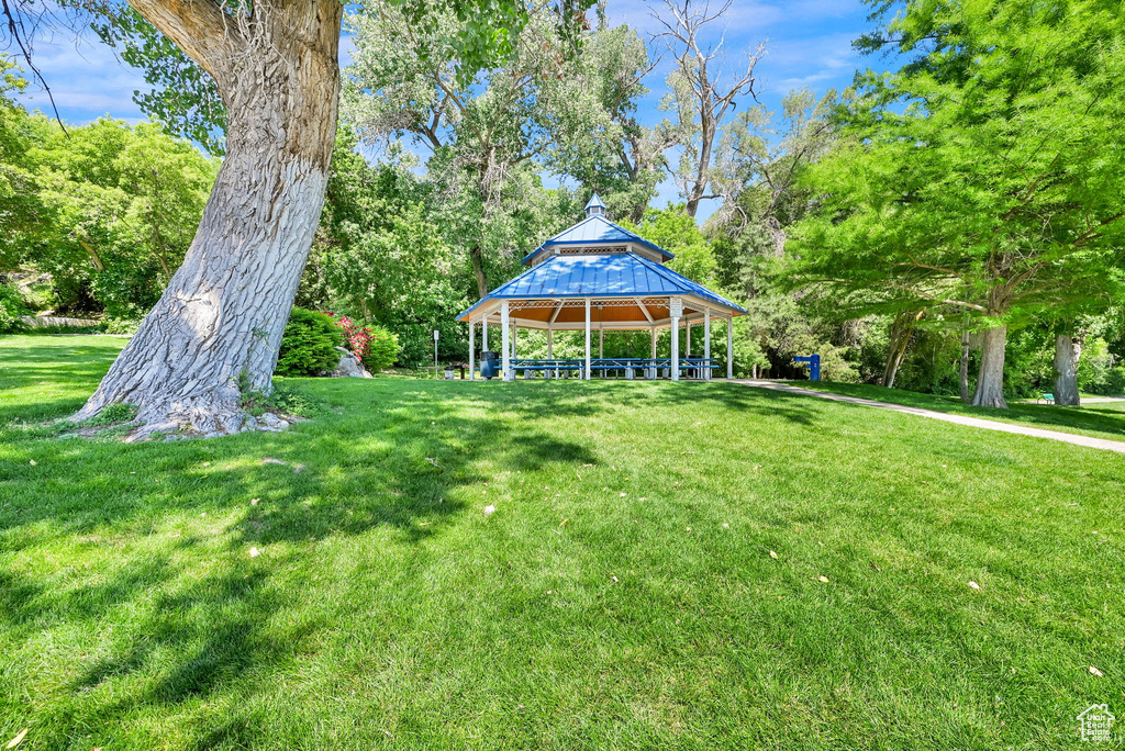 View of green lawn with a gazebo and view of wooded area