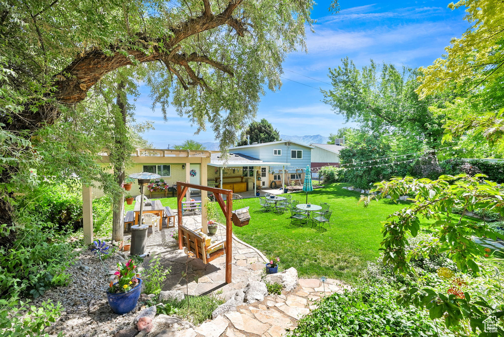 View of grassy yard featuring a patio and an outdoor living space with a fire pit