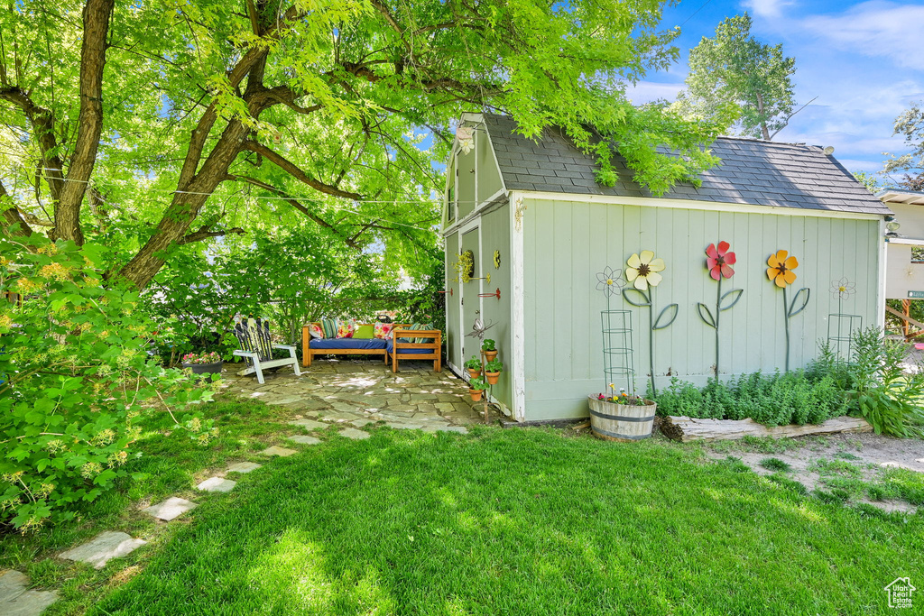 View of green lawn featuring an outbuilding and a patio area
