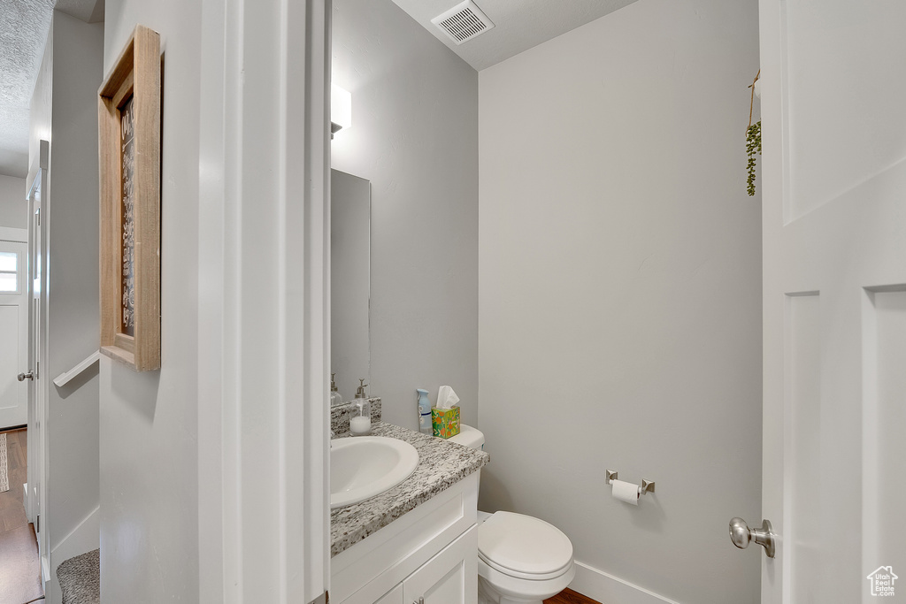Bathroom featuring vanity, toilet, and baseboards