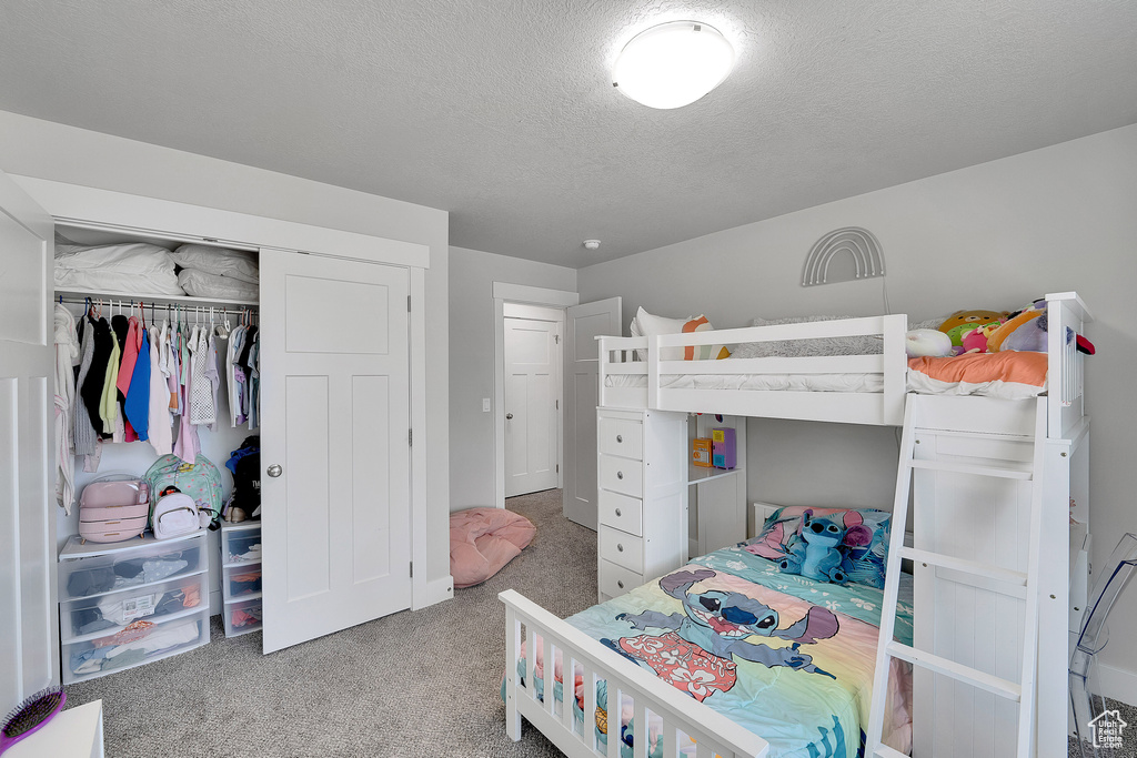 Carpeted bedroom featuring a textured ceiling and a closet