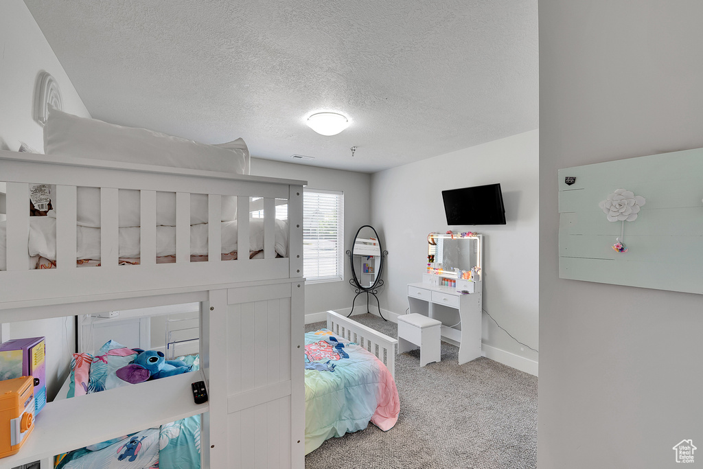 Carpeted bedroom featuring baseboards and a textured ceiling