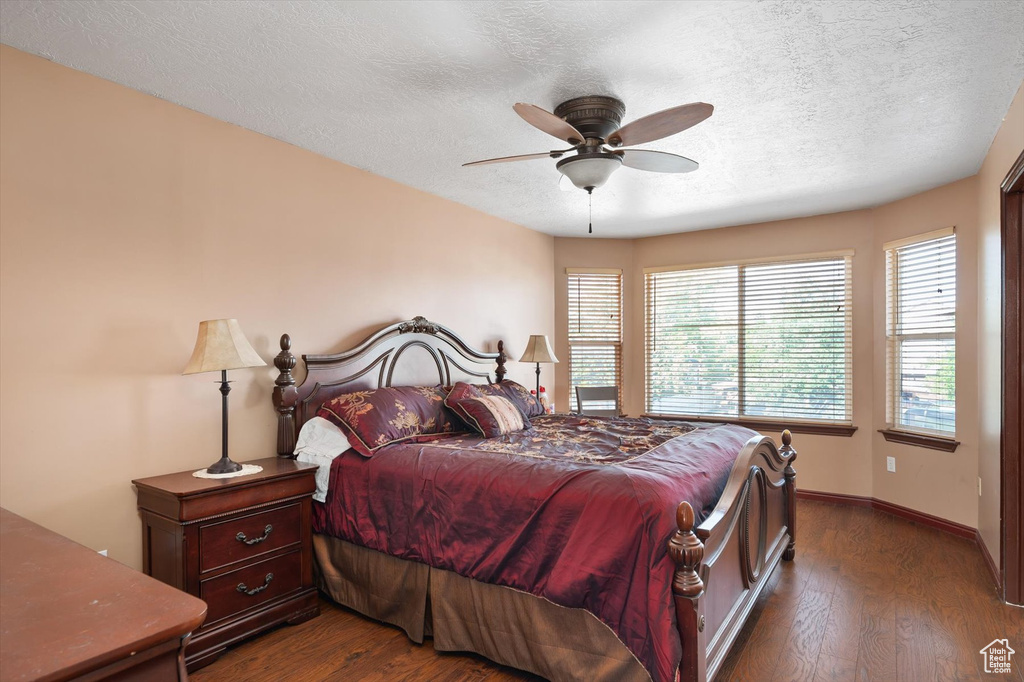 Bedroom with dark wood-style flooring, a textured ceiling, baseboards, and ceiling fan