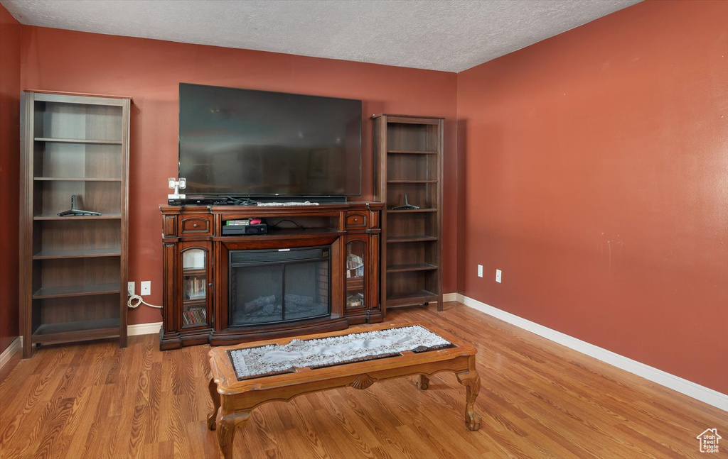 Living area featuring wood finished floors, a textured ceiling, baseboards, and a fireplace