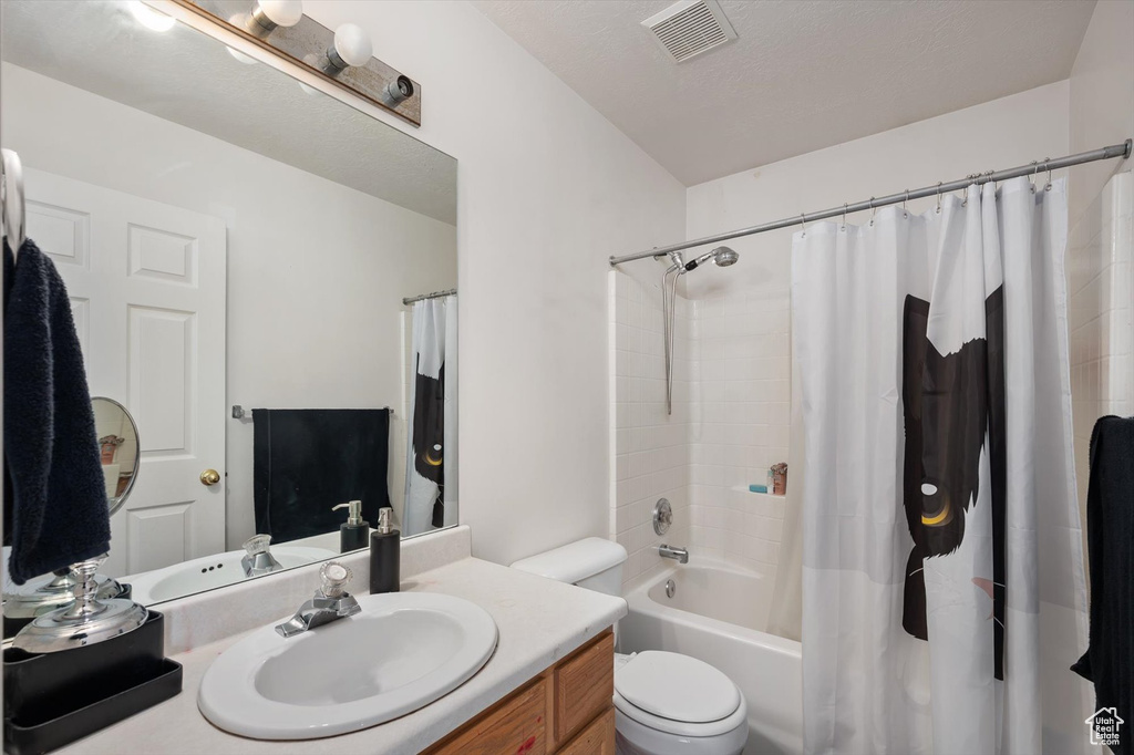 Bathroom with vanity, toilet, and shower / bath combo with shower curtain