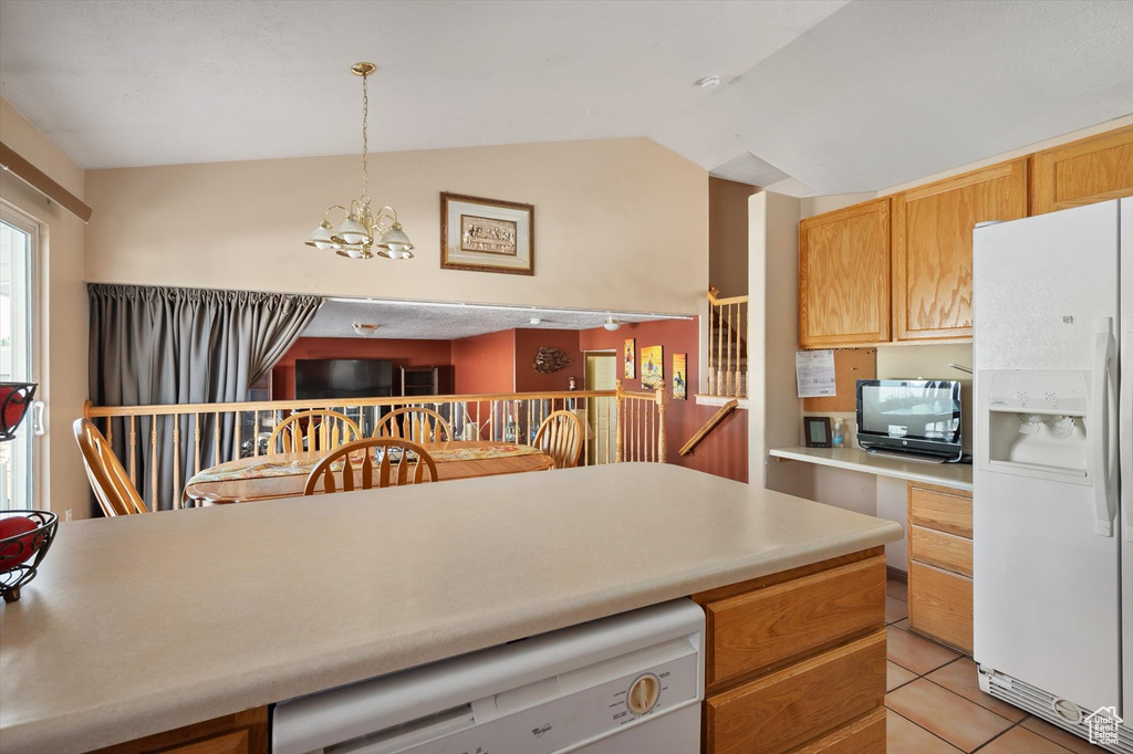Kitchen with white appliances, a chandelier, light countertops, vaulted ceiling, and light tile patterned flooring