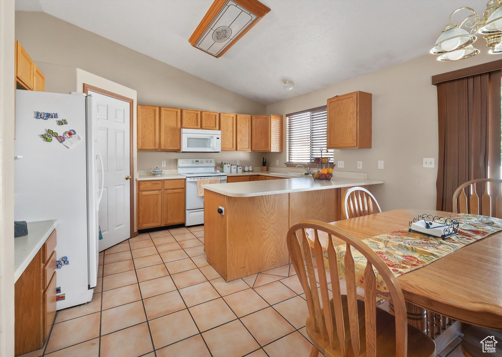 Kitchen featuring white appliances, vaulted ceiling, a peninsula, light countertops, and light tile patterned floors