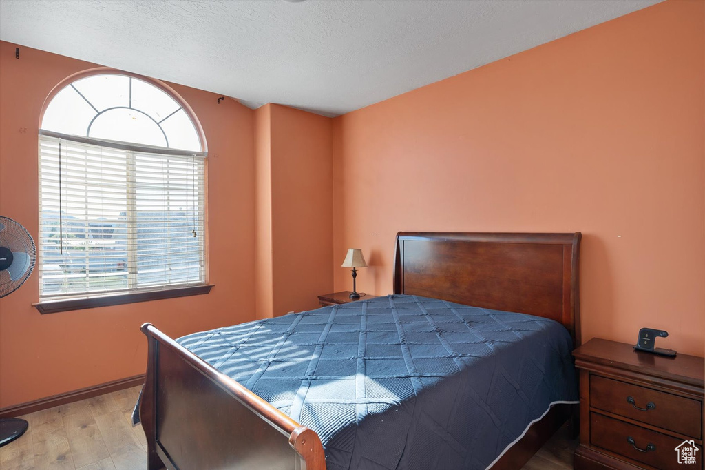Bedroom with wood finished floors, baseboards, and a textured ceiling