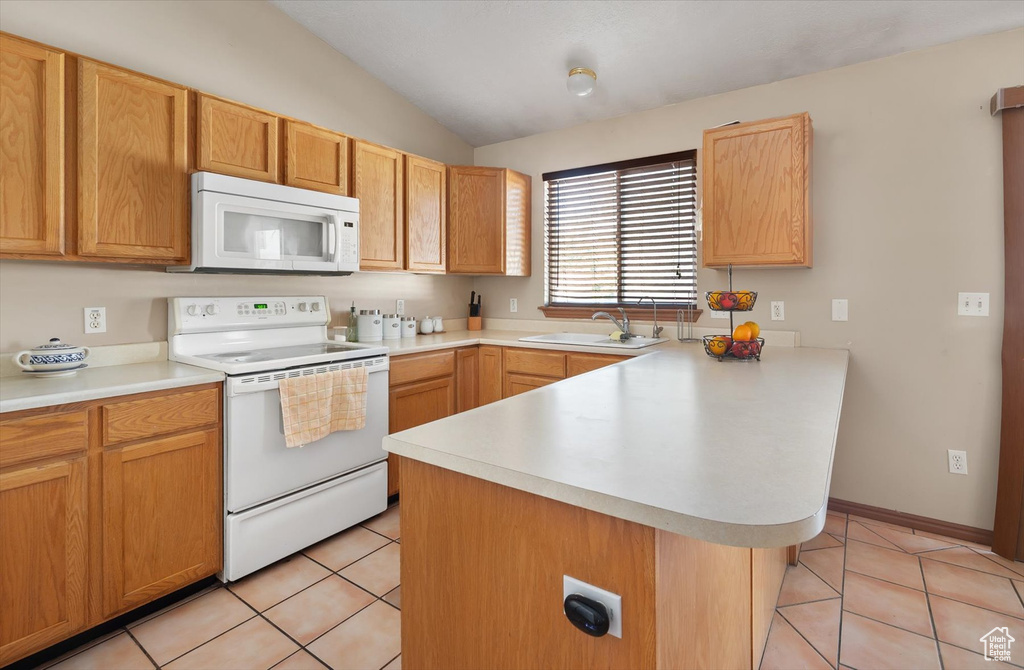Kitchen featuring white appliances, a peninsula, vaulted ceiling, a sink, and light countertops