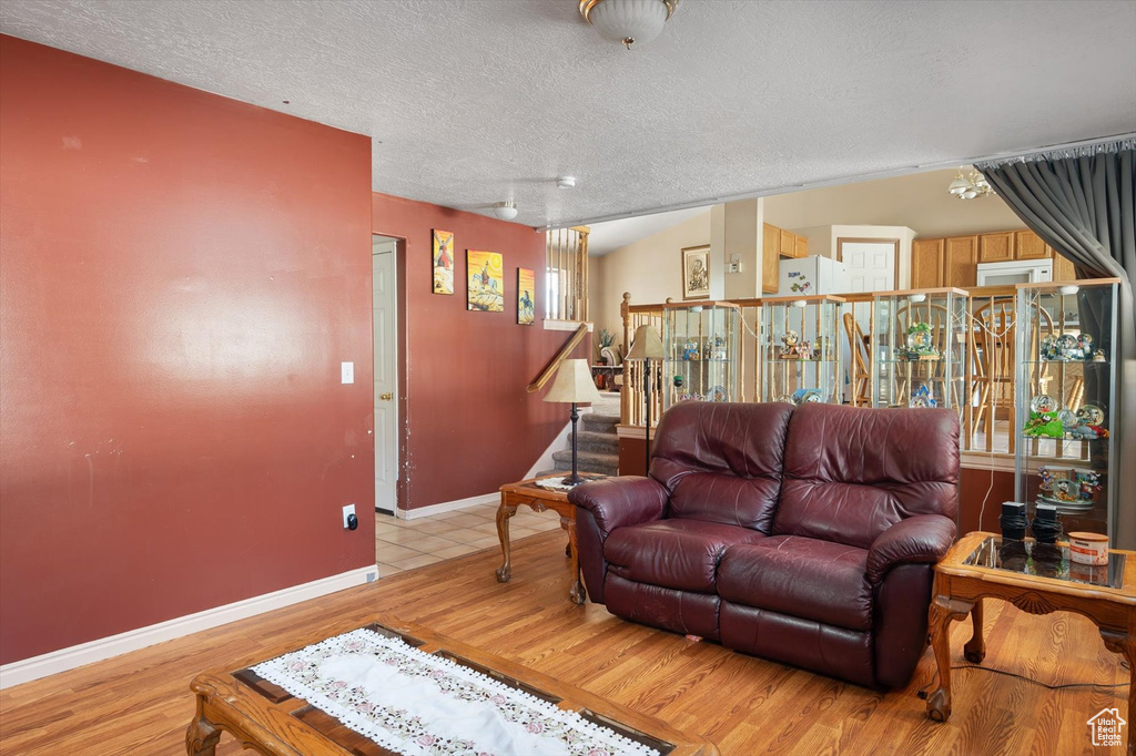Living area featuring light wood-style floors, stairway, a textured ceiling, and baseboards