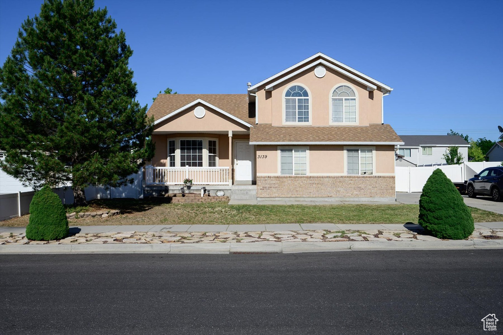 View of front of house featuring stucco siding, covered porch, and brick siding
