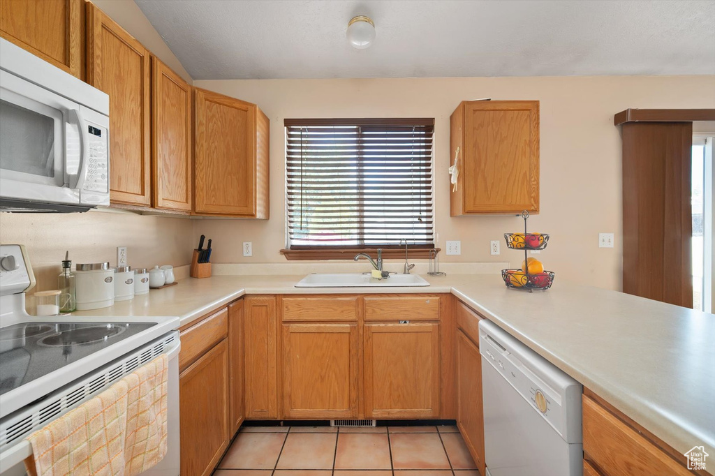 Kitchen with white appliances, a sink, plenty of natural light, and light countertops