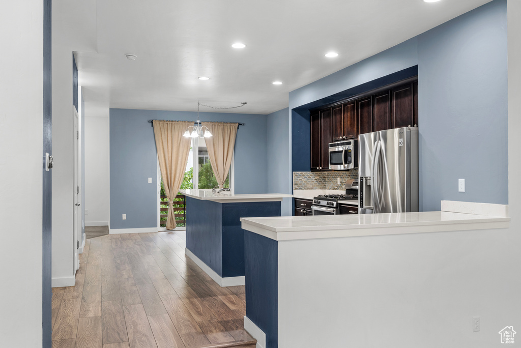 Kitchen featuring stainless steel appliances, light wood finished floors, recessed lighting, light countertops, and decorative backsplash