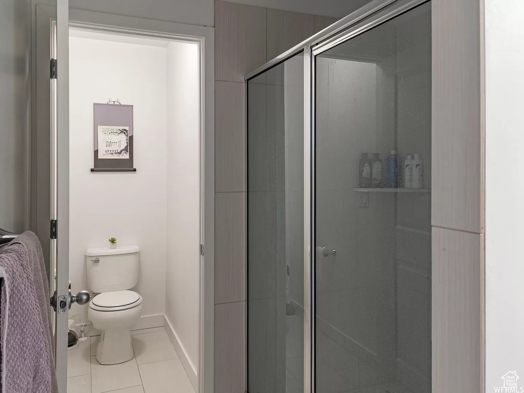 Full bathroom with toilet, a shower stall, tile patterned flooring, and baseboards