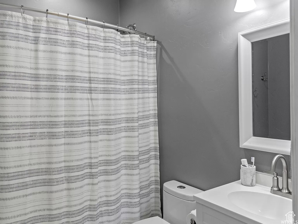 Bathroom with toilet, vanity, and a shower with shower curtain