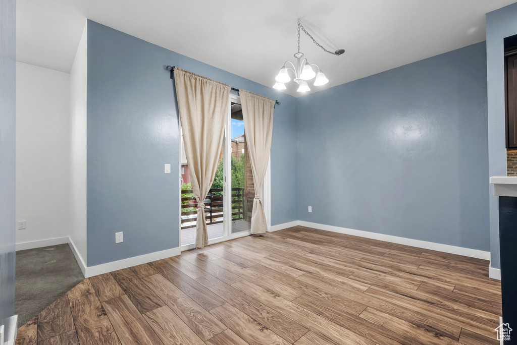 Spare room with a chandelier and wood finished floors