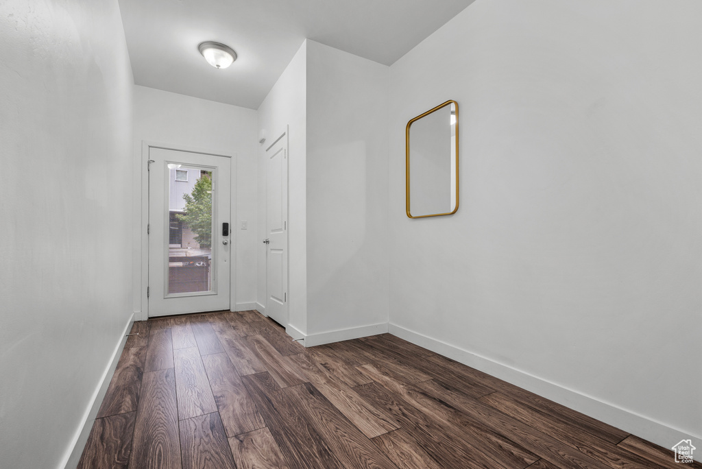 Doorway to outside with dark wood-type flooring and baseboards