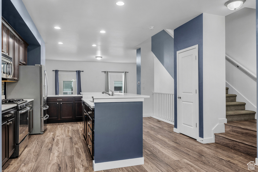 Kitchen featuring stainless steel appliances, a kitchen island, light wood-type flooring, light countertops, and recessed lighting